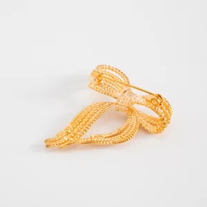 Gold tone bow brooch pin back detail, elegant alloy jewelry accessory for women fashion wear.