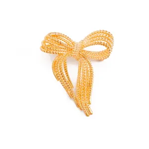 Close-up of the delicate gold multi-strand bow brooch detail, showing shiny texture.