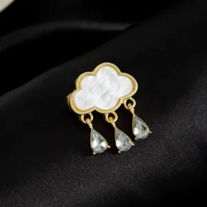 Exquisite gold cloud teardrop tassel brooch detail, elegant white enamel and sparkling crystal.