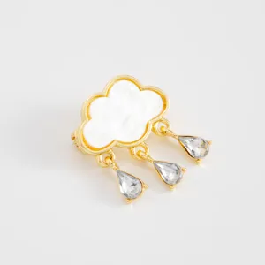 Cloud brooch detail shot showing gold metal, white mother of pearl and crystal teardrop pendants.