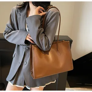Detailed shot of a stylish solid color soft leather large capacity shoulder tote bag worn by model.