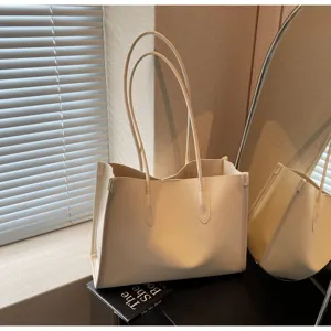 Detail shot of beige soft leather tote bag showing smooth texture and double handle design.