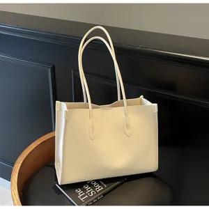 Detail view of a solid color soft leather tote bag on a black stool with a book prop.