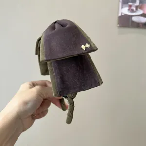 Vue détaillée d'un serre-tête en velours vintage à nœud en vert foncé et violet avec détail doré.