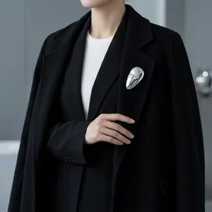 Minimalistische zilveren metalen abstracte broche close-up detail, elegante jas accessoire.