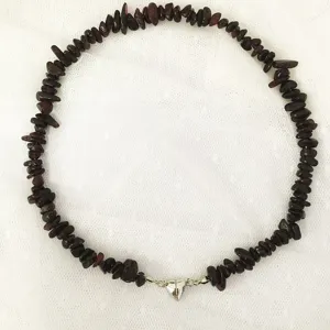 Scatto di dettaglio di collana girocollo con pietre irregolari e chiusura magnetica a cuore.