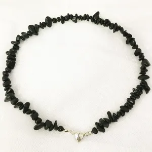 Vista dettagliata della collana di perle in pietra nera irregolare con chiusura magnetica.
