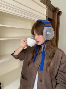 Detail shot of winter knitted earmuffs with plush grey ear warmers and blue ties, cozy style.