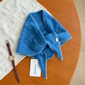 Vista dettagliata della sciarpa triangolare in maglia blu con motivo traforato e bordo.