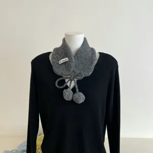 Détail d'écharpe chauffe-oreilles en tricot avec jolis pompons, col d'hiver gris gros plan.