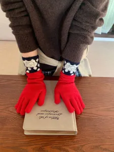 Gros plan détaillé de gants tactiles en tricot rouge avec des poignets à pois charmants.