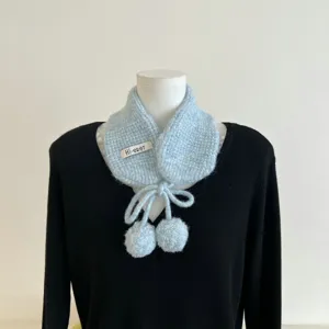 Vue détaillée de la texture de l'écharpe en tricot bleu, fil doux et pompons mignons.