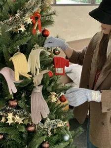 Vista dettagliata di guanti invernali in morbida maglia lavorata su albero di Natale.