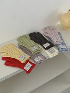 Primo piano dettagliato di guanti invernali in maglia a trecce colorati su scaffale.
