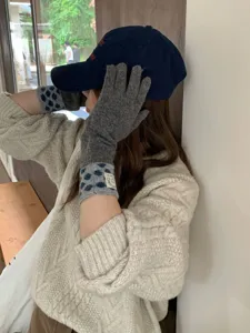 Gros plan de gants longs en tricot à pois de style coréen portés par le modèle en hiver.
