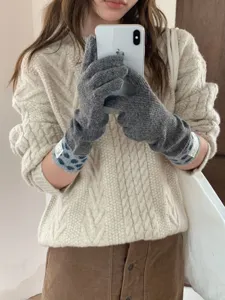 Gros plan de gants tactiles en tricot chaud d'hiver avec des poignets à pois mignons.