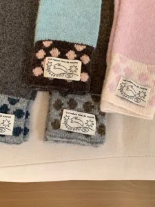 Gros plan détaillé de gants longs tricotés d'hiver douillets avec pois et étiquette.