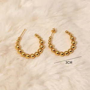 Vista detallada de pendientes de aro de acero inoxidable dorado con un elegante diseño en forma de C.