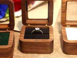Boite a bague en bois de noyer avec couvercle transparent et fente en velours noir.