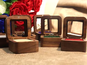 Gros plan détail de boîte à bague en bois massif avec couvercle en verre et fente en velours.