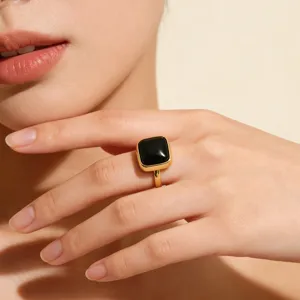 Primer plano de un anillo de mujer ajustable de oro con una elegante piedra preciosa negra.