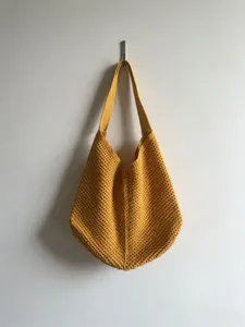 Detailed view of the yellow crochet shoulder tote bag showing its hollow-out knit texture.
