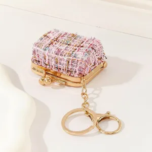 Detailaufnahme des rosa Tweed Mini Tasche Anhängers mit goldenem Metallbügel und Schlüsselring.