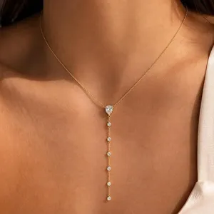 Délicat collier Y doré avec pendentifs en forme de goutte étincelante et pierres rondes.