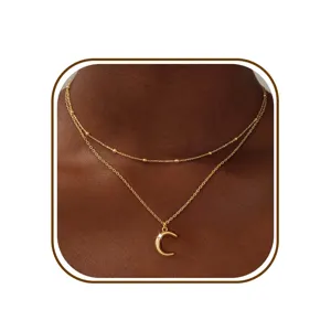 Close-up van een elegante dubbele gouden ketting versierd met een subtiele maan hanger.