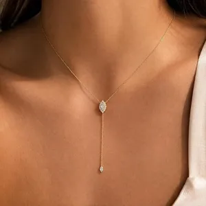 Détail délicat de collier Y doré avec pendentif étincelant en cristal de forme marquise.