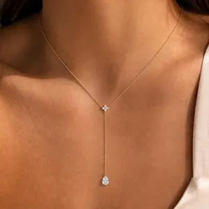Détail de collier en Y doré délicat avec pendentif poire scintillant et centre floral.