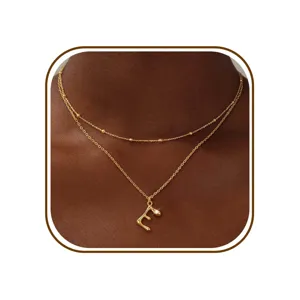 Gouden dubbellaagse ketting detail met letter E hanger en prachtige delicate kraalketen.