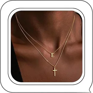 Collier double doré superposé avec lettre E et pendentif croix pour femmes élégantes.