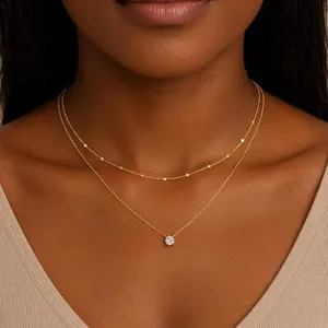 Élégant collier double en or avec perles délicates et pendentif en zircone étincelant.