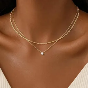 Gros plan sur le collier doré double élégant avec un pendentif en zircone cubique étincelant.