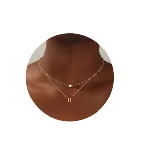 Primer plano detalle de collar gargantilla doble de oro con letra R y corazón.