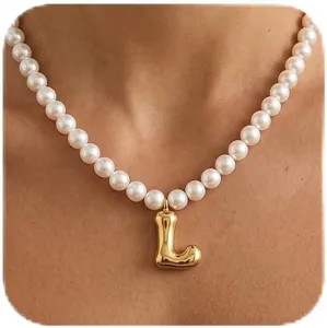Nahaufnahme des goldenen Buchstaben-L-Anhängers und der weißen Perlen-Choker-Halskette.