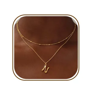 Detailopname van een minimalistische gouden dubbellaags ketting met elegante N-letterhanger.