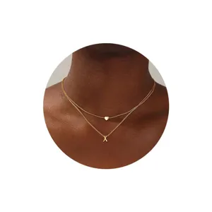 Collar inicial dorado de doble capa con dije de corazón, joyería minimalista elegante.