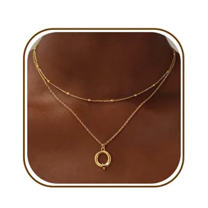 Gedetailleerde close-up van een dubbellaags gouden ketting met fijn kralenketting en hanger.