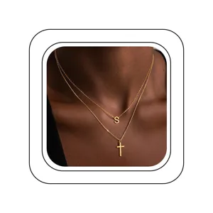 Vue détaillée d'un élégant collier double en or avec pendentif lettre S et croix.