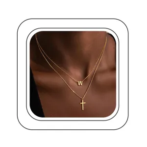 Gros plan détaillé du collier doré double couche avec pendentif lettre W et croix.