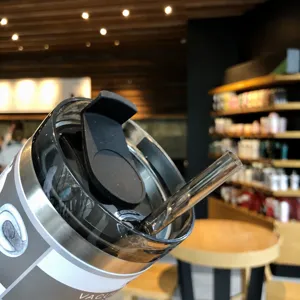 Stainless steel insulated tumbler detail view, featuring clear lid and straw for easy drinking.