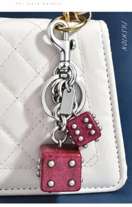 Gros plan sur un porte-clés dés roses scintillants avec des accessoires en métal argenté.