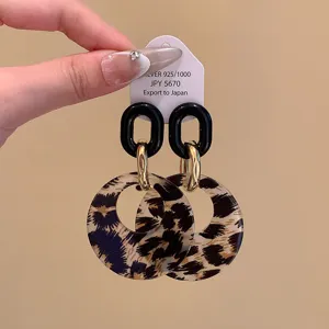 Retro luipaardprint en amber hangende oorhangers met zwarte schakels en gouden ringen.