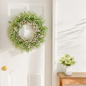 Detail view of artificial floral wreath hanging on a white door with cozy home decor.
