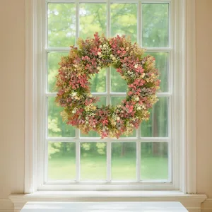 Close-up detail of a vibrant artificial eucalyptus floral wreath hanging on a clear glass window.