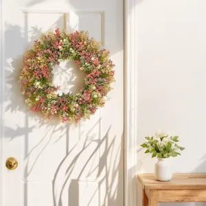 Detailed view of the colorful artificial flower wreath hanging on a white door in home decor.