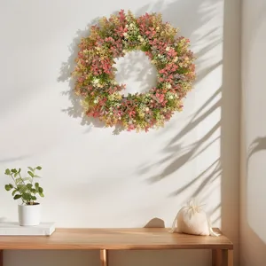 Artificial eucalyptus wreath detail display with green pink foliage for indoor wall decor.