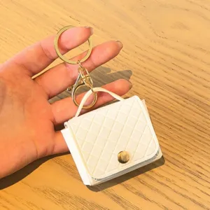 Close-up van witte gewatteerde mini handtas sleutelhanger, elegante PU lederen portemonnee.
